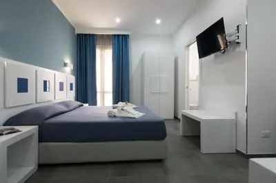 a bedroom with a blue bed and a television at Pharos in San Vito lo Capo