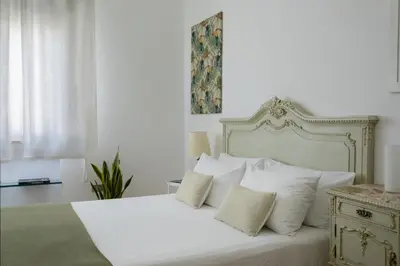 a bedroom with a white bed with white pillows at Le case di Frelli in Palermo
