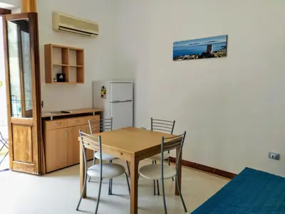 a kitchen with a table and chairs and a refrigerator at Appartamenti Blu Mare in Castellammare del Golfo