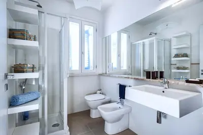 a white bathroom with a sink and a toilet at Lisca Bianca in San Vito lo Capo