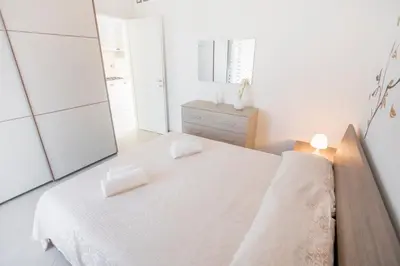 a white bedroom with a bed and a mirror at Le Zagare in Lascari
