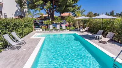 a pool with chairs and umbrellas next to a house at Le Zagare in Lascari
