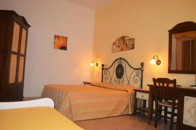 a bedroom with two beds and a table and a desk at Kimos in San Vito lo Capo