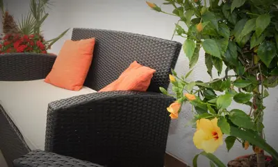 a wicker chair with two orange pillows on it at Kimos in San Vito lo Capo