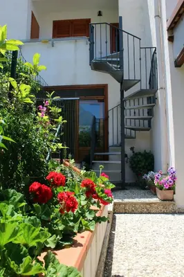 a garden with red flowers and a spiral staircase at Raggio di Sole Bed & Breakfast in Macari