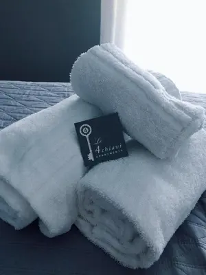 a pile of white towels on a bed with a book at Le Quattro Chiavi in Palermo