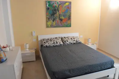 a bedroom with a bed and a painting on the wall at Le Gemme di Sicilia Apartments in Castellammare del Golfo