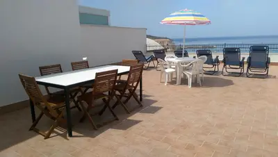 a patio with tables and chairs and an umbrella at Appartamenti Via Marconi in Castellammare del Golfo
