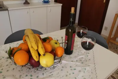 a basket of fruit on a table with two glasses of wine at Appartamenti Via Marconi in Castellammare del Golfo