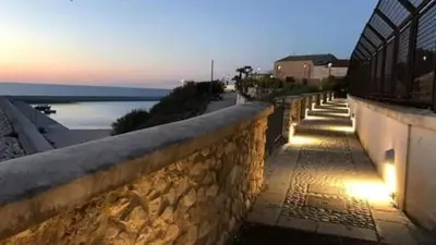 a stone wall next to a beach at sunset at Casa Josephine in Balestrate