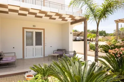 a patio of a villa with palm trees at La Blanca Resort & Spa in Castellammare del Golfo