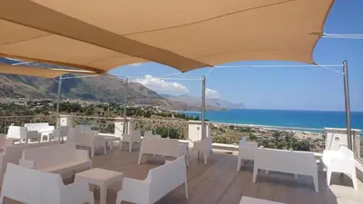 a balcony with white chairs and a view of the ocean at La Blanca Resort & Spa in Castellammare del Golfo