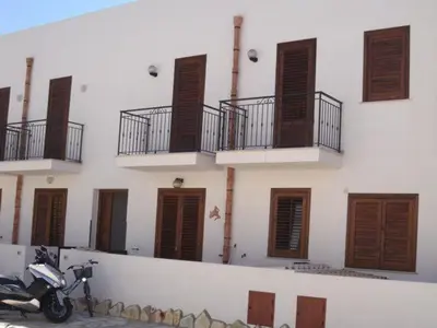 a motorcycle parked in front of a building with windows at Case nel Giardino in San Vito lo Capo