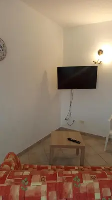 a bedroom with a bed and a tv on the wall at Case nel Giardino in San Vito lo Capo