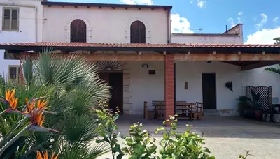a large white house with a porch with a table at Il Gelsomino Home Holiday in Alcamo