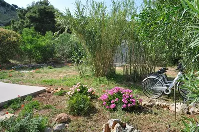 a bike parked in a garden with flowers at Villetta Blusanvito in San Vito lo Capo