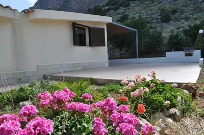 a garden with pink flowers in front of a house at Villetta Blusanvito in San Vito lo Capo