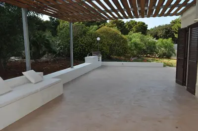 a patio with a white couch and a wooden roof at Villetta Blusanvito in San Vito lo Capo