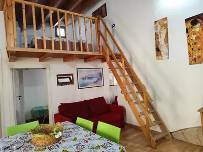 a living room with a red couch and a wooden staircase at La Perla sul Golfo in Castellammare del Golfo
