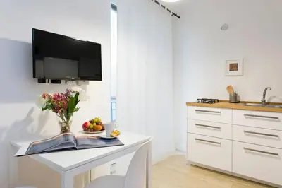 a kitchen with a white table with a tv on the wall at BB4U Apartments in Palermo