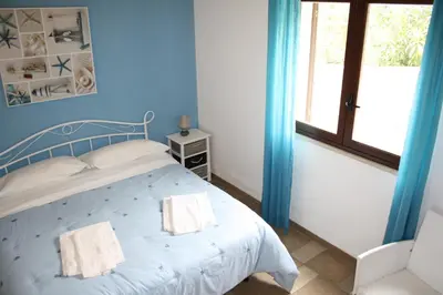 a blue bedroom with a bed and a window at Villa Rossana in Scopello
