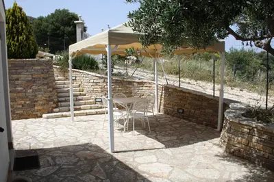 a table and chairs under an umbrella on a patio at Villa Rossana in Scopello