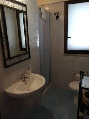 a bathroom with a sink and a toilet and a mirror at Villa Rossana in Scopello