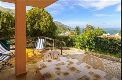 a table and chairs on a patio with a view of the ocean at Two Steps From The Sea in Scopello