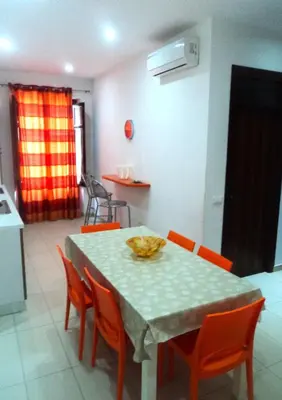 a dining room table with orange chairs and a kitchen at Orange House a Castellammare del Golfo in Castellammare del Golfo