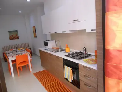 a kitchen with a stove and a table in it at Orange House a Castellammare del Golfo in Castellammare del Golfo