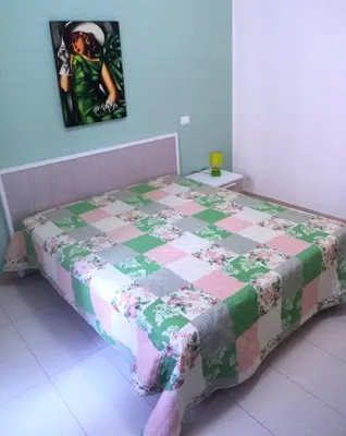 a bed with a quilt on it in a room at Orange House a Castellammare del Golfo in Castellammare del Golfo