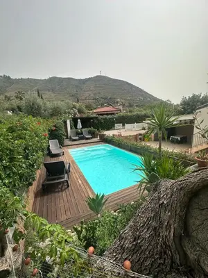 a swimming pool on a wooden deck next to a house at Villa Giorgia in Cefalù