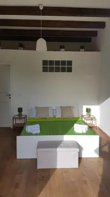a white bedroom with a large bed with green sheets at Mondello Sicily House in Mondello