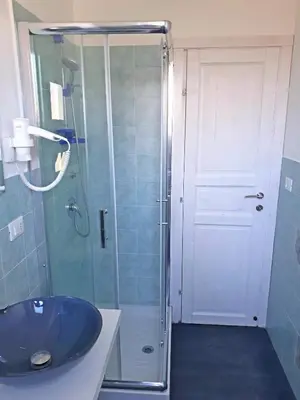 a bathroom with a glass shower with a blue sink at Mondello Sicily House in Mondello