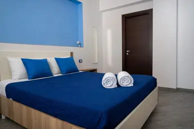 a bed with blue and white pillows on it at A Mare Appartamenti in Castellammare del Golfo