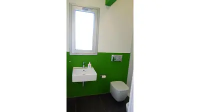 a green bathroom with a sink and a toilet at Casamatta in Trappeto