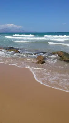 a beach with rocks and the ocean with waves at Casamatta in Trappeto