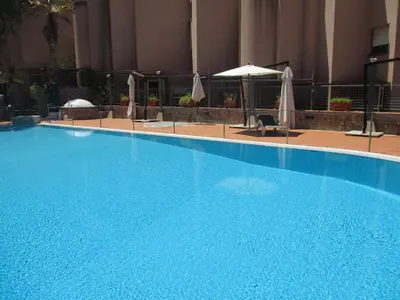 a large blue swimming pool with chairs and umbrellas at Mondello Addaura Home Holiday in Mondello
