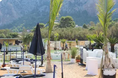 a resort with chairs and umbrellas and palm trees at Mondello Addaura Home Holiday in Mondello