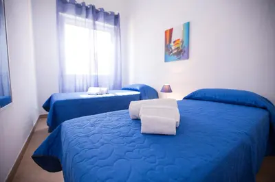 a bedroom with two blue beds and a window at Appartamento Nettuno in Castellammare del Golfo