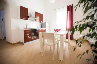 a white kitchen with a white table and chairs at Appartamento Nettuno in Castellammare del Golfo