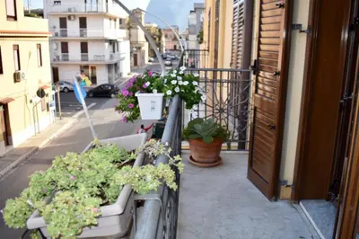 a balcony with potted plants on a city street at Alma Nua in Terrasini