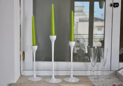 four green candles inront of a window with wine glasses at Alma Nua in Terrasini
