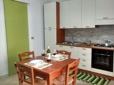 a kitchen with a wooden table with two chairs at Carpe Diem Apartments in Castellammare del Golfo