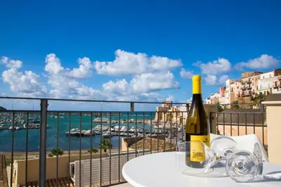 a bottle of wine on a table with a view of a harbor at N'amuri Residence in Castellammare del Golfo