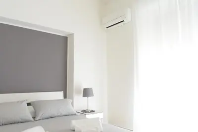 a white bedroom with a bed and a window at Caselita in Palermo