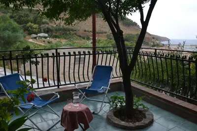 two chairs and a table and a tree on a balcony at Aura Maris in Castellammare del Golfo