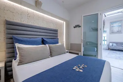 a bedroom with a large bed with blue pillows at Hotel Soffio D'Estate in San Vito lo Capo