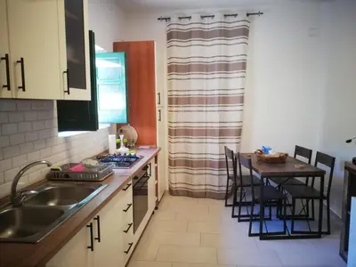 a kitchen with a sink and a table with chairs at Villa Buonasera in Santa Flavia