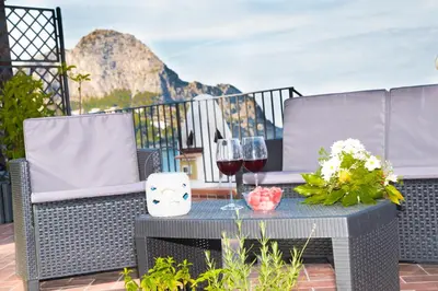 a table with wine glasses and flowers on a patio at Villa Buonasera in Santa Flavia